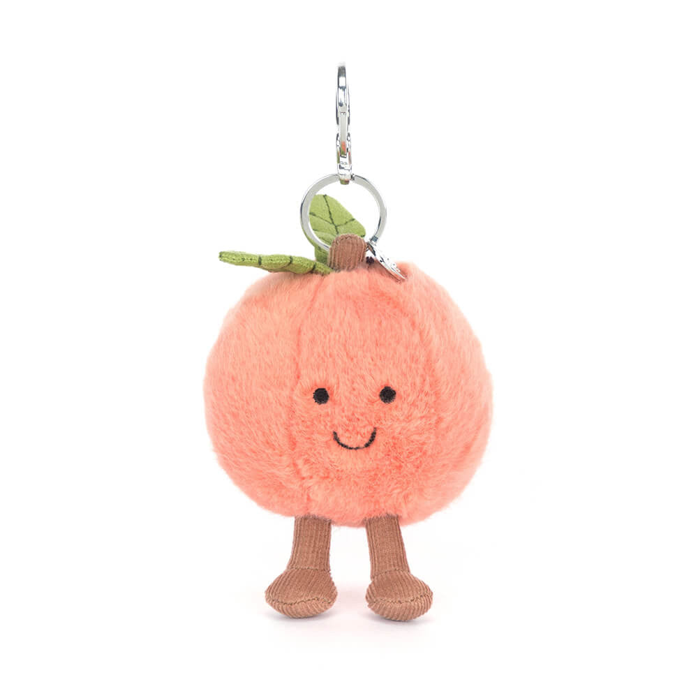 Jellycat peach plush keychain with a smiling face and brown feet on a white background.