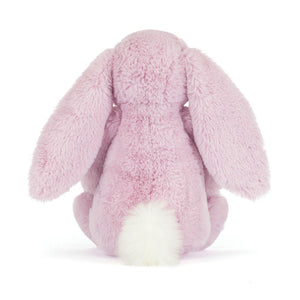 Back view of a Jellycat lilac plush bunny with a white fluffy tail on a white background. 