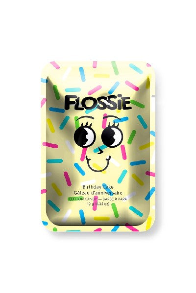 light yellow rectangular bag with "Flossie" written in black and a cartoonish facial expression at the centre. the flavour of the candy is written in a smaller font below the grimace. colourful sprinkles fill the empty spaces on the bag
