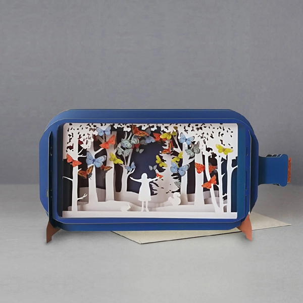 blue bottle pop up card. the intricate paper cuttings depict a white forest scene with a character's silhouette looking up at colourful butterflies