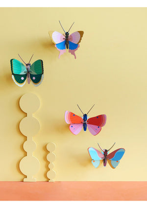 Four colourful 3D butterfly wall decorations on a yellow and orange background.