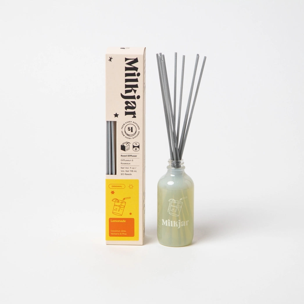 Milkjar diffuser bottle containing reeds and placed beside packaging with the store branding on a white background.