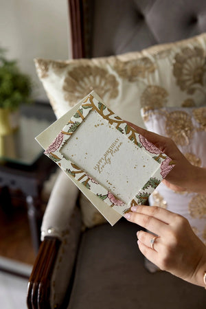 Hands holding a photo frame cotton card with a pink, green and gold botanical design and 'Happy Birthday Lovely Person' text. 