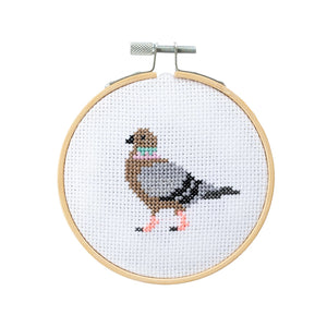 Cross-stitched pigeon design in a wooden hoop on a white background.