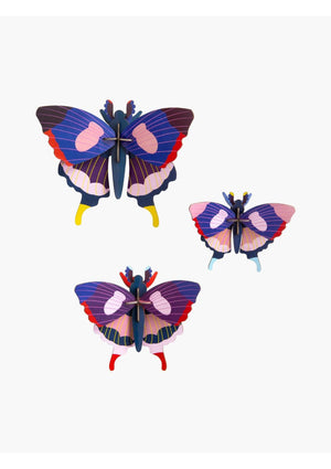 Three 3D swallowtail butterflies hanging on a white background. The butterflies are blue, pink, white, purple and red in colour. 