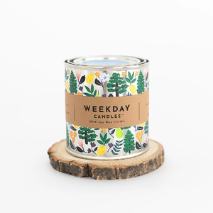 silver tin candle with painted doodles of trees, lemons, pears, and flowers. a brown tag wraps the tin. on it, "Weekday Candles 100% Soy Wax Candle", the name of the product, the ingredients and instructions are written in a sharp black font.