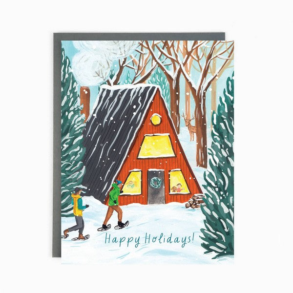 A Christmas card featuring a cottage with a snowy landscape, a man and a woman skiing in front of the cottage, and holiday greetings.
