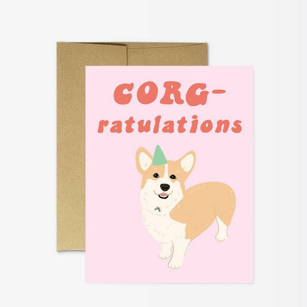 pink congratulations card with an illustrated corgi wearing a green party hat. top text reads "corg-ratulations"